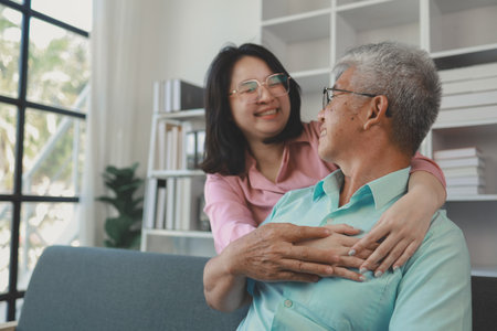 A father and daughter sat in the living room happily spending time together after not seeing each other for a while, A warm family is in the house, Elderly father and teenage daughterの写真素材