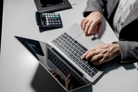 A young businessman is using a laptop to search for important information on business competitors, A...