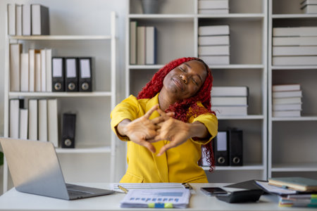 Beautiful African businesswoman relaxes after resting from long hours of hard work, The beautiful African employee felt very happy because the work she was responsible for was completed successfully.の写真素材