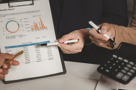 Colleagues scrutinize calculated numbers to discuss which number is correct in a conference room, A group of businessman use a calculator to perform calculations and exchange results with each other.の写真素材