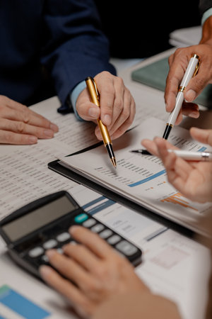 A group of three businesspeople are working together to calculate the company's numbers, employees are meeting about an important document that has many numbers that must be carefully calculated.の写真素材