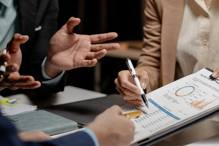Three businesspeople are brainstorming together in a conference room about documents that need to be edited on the table, Colleagues are exchanging ideas about business strategies.の写真素材