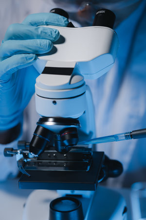 A scientist is studying samples using a microscope to study and develop the field of microbiology,...