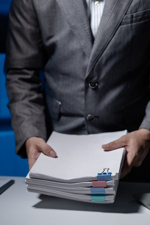 An employee was tidying up a pile of documents piled on his desk before returning home from work, A...