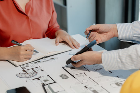 Engineers and colleagues are working to calculate the space in the various rooms of the blueprint to create a solution that meets international standards.の写真素材