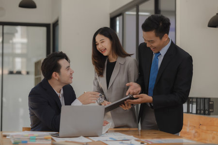 A group of employees happily work together in the office while discussing work that was completed on...
