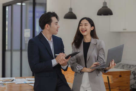 A group of employees happily work together in the office while discussing work that was completed on...