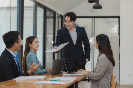 A group of employees happily work together in the office while discussing work that was completed on time as ordered by their boss, A group of entrepreneurs had fun working together.の写真素材