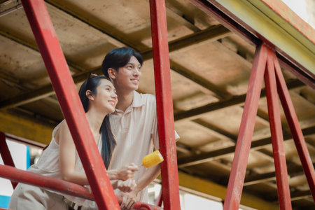 this adorable couple is eating and walking around at street food with happiness, they are dating on weekend at market, smiling because both of them are super satisfy being a coupleの写真素材