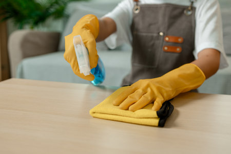 the young lady is doing housework, a wife is cleaning the house of her family, wearing gloves to...