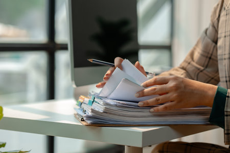 a secretary is organizing stack of paperwork for keep her desk clean, tidy up all finance document...