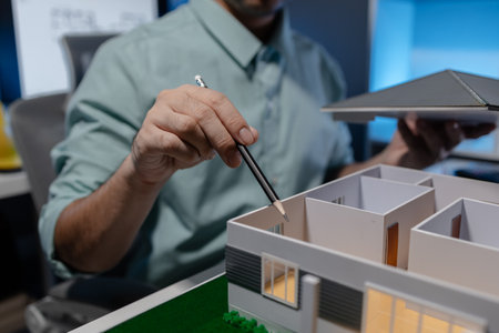 an architect is working in the office, an engineer works on house model on the desk, he used his expertise skill and creativity to design the best work for the clientの写真素材