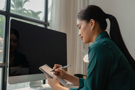 a businesswoman sit in her office, she is planning by searching on website for information to start a startup company, en entrepreneur is working in front of computerの写真素材
