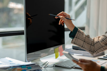 a businesswoman works at her desk, an entrepreneur is sitting and working in front of the computer to research for information on new project, female employee is in the officeの写真素材