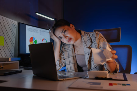 a businesswoman is feeling exhausted and stressed because of she has to work overtime from overworked, she get upset of task that she has to finish because deadline is comingの写真素材