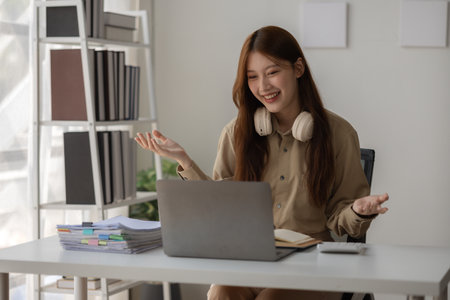 an Asian beautiful businesswoman and her team are discussion via video conference with her client about planing of new strategy, a CEO is meeting with her team via video call in her private office,の写真素材