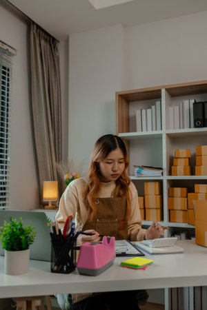 an entrepreneur or a business owner works in her office full of packages, it is a small business that she created with careful preparation, start up business of clothesの写真素材