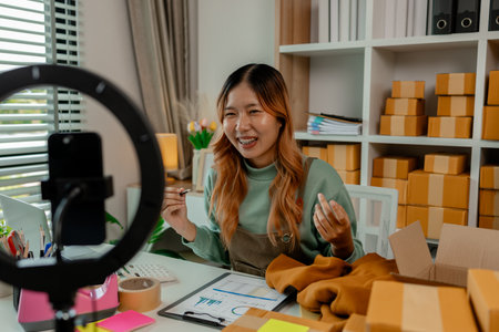the business owner or an entrepreneur is doing live marketing to sell her products that is clothing through online channels for all customers who like to do online shoppingの写真素材