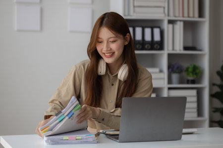 a businesswoman is doing her job in the office with smile on her face, an employee is happily working in workplace, a beautiful CEO works hard but happy in her companyの写真素材