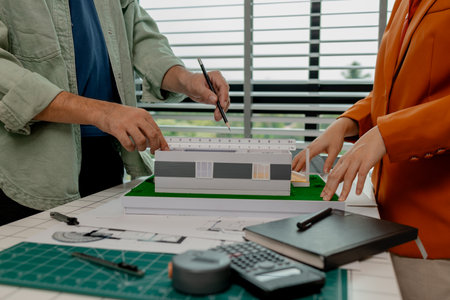 An architect and engineer work as a team, an engineer is discussing with coworker about detail of...
