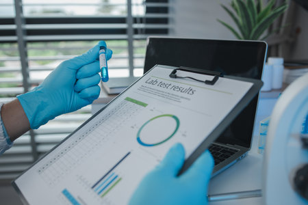 A scientist is reviewing lab results and documents receives from researchers involved in chemical testing, chemist is concentrating on reading test results documentの写真素材