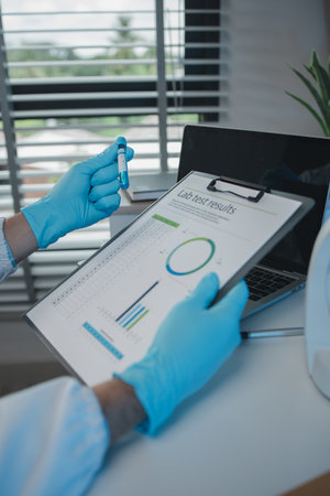 A scientist is reviewing lab results and documents receives from researchers involved in chemical testing, chemist is concentrating on reading test results documentの写真素材