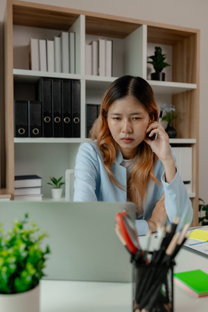 a businesswoman feels stressed and tired from work about the deadline, an employee feels worried wile sitting at work in the office, serious work causes stress during work,の写真素材