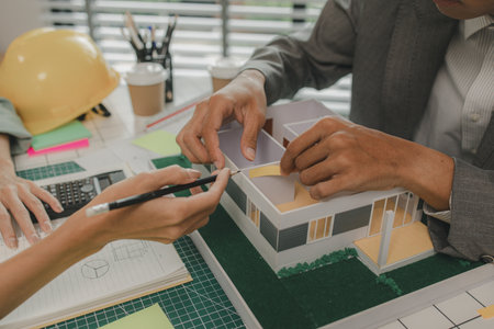 engineer and investor are negotiating the details of a housing project that will soon be built, an architect is consulting with an engineer about designing a house structure to meet the client's needsの写真素材