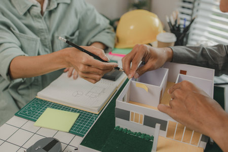 engineer and investor are negotiating the details of a housing project that will soon be built, an architect is consulting with an engineer about designing a house structure to meet the client's needsの写真素材