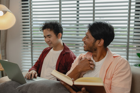 two beautiful guys spend their time together in the living room as a couple, romantic relationship between two handsome, males live together as a couple in their house happily.の写真素材