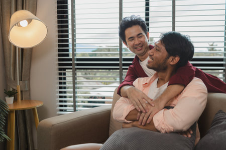 a male couple is spending time together happily in their living room, two handsome guys have a beautiful friendship for a long time, this male couple looks cute together, romanticの写真素材