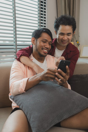 a male couple is spending time together happily in their living room, two handsome guys have a beautiful friendship for a long time, this male couple looks cute together, romanticの写真素材