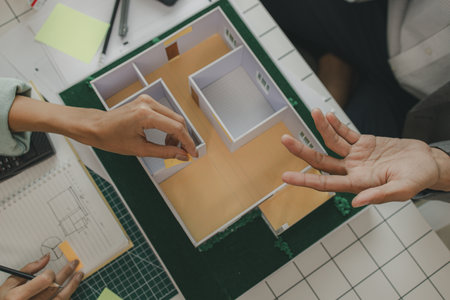 a foreman is consulting with an engineer about house structure, n architect and assistant are...