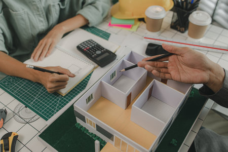 engineer and investor are negotiating the details of a housing project that will soon be built, an architect is consulting with an engineer about designing a house structure to meet the client's needsの写真素材