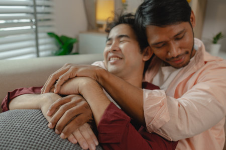 two beautiful guys spend their time together in the living room as a couple, romantic relationship between two handsome, males live together as a couple in their house happily.の写真素材