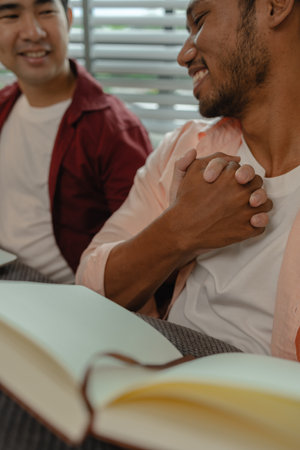 two beautiful guys spend their time together in the living room as a couple, romantic relationship between two handsome, males live together as a couple in their house happily.の写真素材