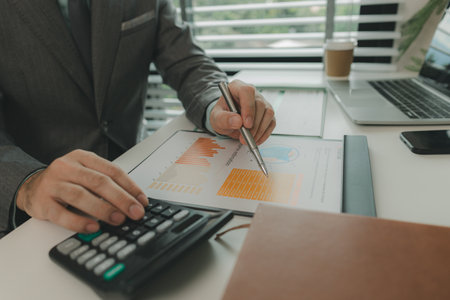 Typical office work atmosphere for company employees. A businessman is diligently handling important documents in his personal office. Important project report documents are being analyzed by experts.の写真素材