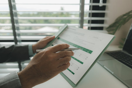 a businessman is in his private office and working with a lot of paperwork, a senior executive of marketing company is checking income report of this year, analyzing documentの写真素材