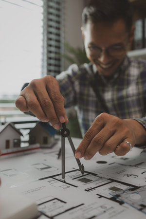 A team of engineers meets in the office to analyze the design structure to ensure it meets the client's wants. A team of architects and contractors meets to discuss the design based on a model house.の写真素材