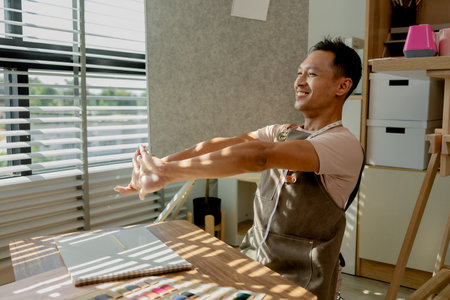 a fashion designer dis taking a break in his sewing studio after working all morning, a tailor is spending his free time in his workshop, which is filled with design and sewing equipmentの写真素材