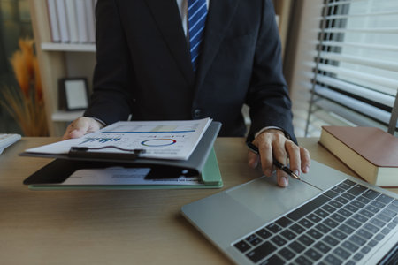 A businessman is sitting in an office with documents in his hands to analyze data. An executive of a...