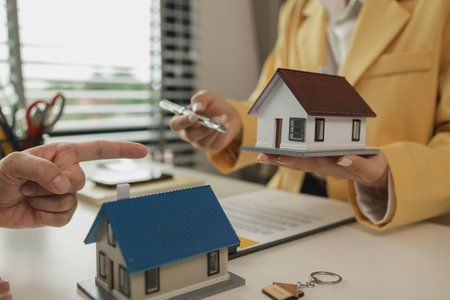 A man comes to a real estate agent for consultation about the house he is buying to start his family. The buyer comes to sign a purchase agreement with the agent.の写真素材