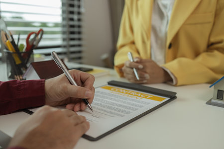 A man signs a contract after agreeing to buy a house with an agent. The agent explains the details of the contract to the buyer before signing it. Home purchase contractの写真素材