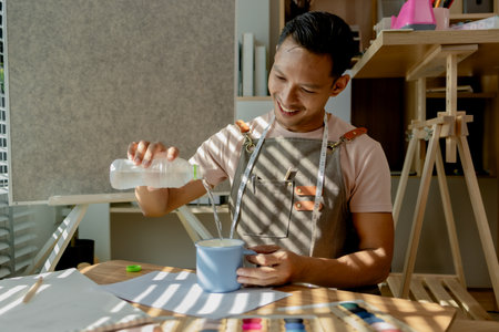 a fashion designer dis taking a break in his sewing studio after working all morning, a tailor is spending his free time in his workshop, which is filled with design and sewing equipmentの写真素材