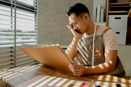 a fashion designer is under a lot of stress because he cannot figure out what his new collection will look like, his motivation to work is decreasing, skill, clothes, idea, fashionableの写真素材