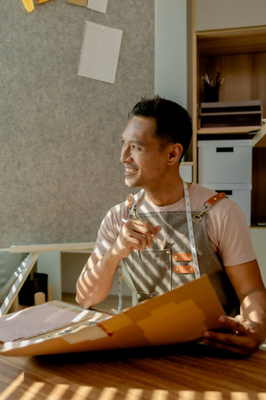 a tailor is happily sketching a dress in his studio, a fashion designer is sketching his new collection on sketch paper before making it into a complete dress, clothes, fashionable, stylish, createの写真素材