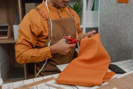 designer shop owner is working in his studio, use a lot of fabric to make clothes, design fashionable clothes for customer, sewing is an important tool for designer.の写真素材