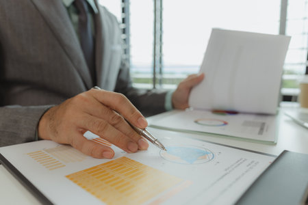 Typical office work atmosphere for company employees. A businessman is diligently handling important documents in his personal office. Important project report documents are being analyzed by experts.の写真素材