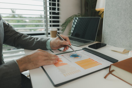 a businessman is in his private office and working with a lot of paperwork, a senior executive of marketing company is checking income report of this year, analyzing documentの写真素材