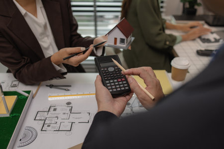 an architect is working in the office with his team, blueprint on the desk, contractor working with an engineer team, engineering and architecture, house model on the deskの写真素材